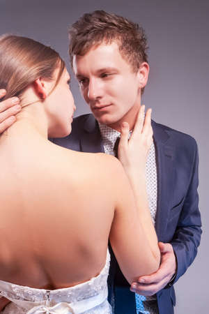 Positive caucasian Couple in Love Embracing Together. Woman Posing in Wedding Dress Against Gray.Vertical Imageの写真素材