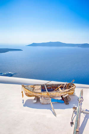 Old Wooden Boat on White roof in Thira Against The Aegean Sea and The Chain of Islands in Santorini. Vertical Imageの写真素材