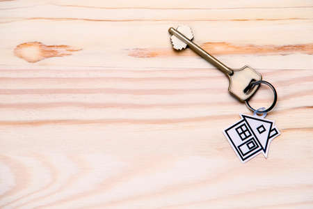 Family and Home Concepts. Home or House Symbol Along With Golden Key Over Vintage Wooden Background. Toned Image. Horizontal Compositionの写真素材