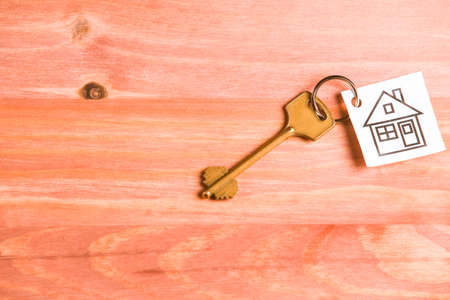 Family and Home Concepts. House Symbol Along With Golden Key Over Vintage Wooden Background. Horizontal Imageの写真素材