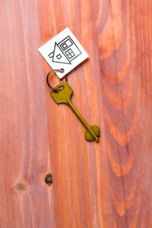 Family and Home Concepts. House Symbol Along With Golden Key Over Vintage Wooden Background. Vertical imageの写真素材
