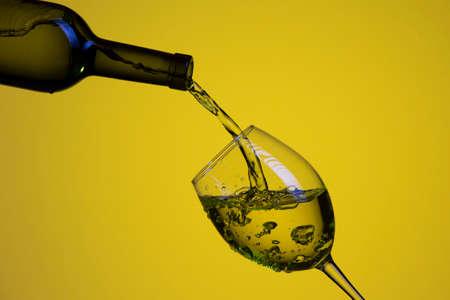 Drink Pouring Out of The Bottle On The Left Hand Side to Whineglass with Colorful Liquid and...