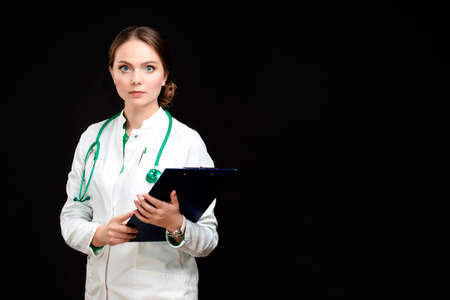 Medicine Concepts. Portrait of Professional Female GP Doctor Posing in Doctor's Smock and Endoscope Against Black.Horizontal Image Orientationの写真素材