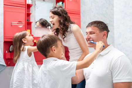 Family Concepts. Young VCaucasian Fa,ily with The Kids Having Fun in Bathroom While Brushing Teeth Together. Horizointal Image Orientationの写真素材