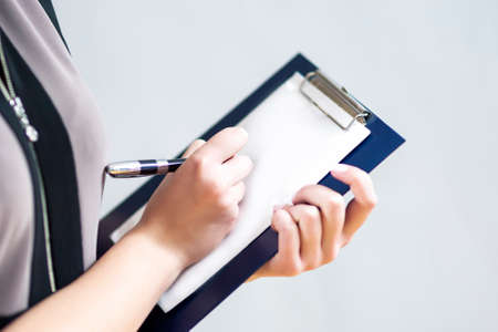 Closeup of Hands of Caucasain Woman Writing on Paper Sheet on Notepad.Horizontal Image Orientationの写真素材