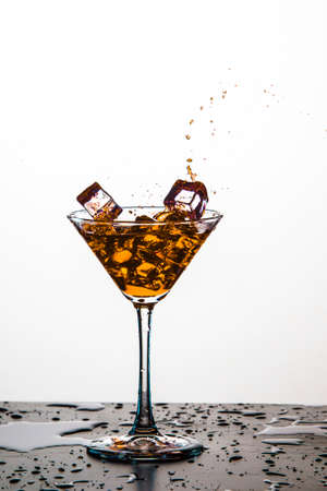 Colorful Liquid Droplets With Ice Cubes Falling to Goblet. Against White Background. Vertical Image...