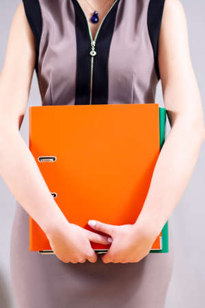Closeup of Hands of Caucasian Female Holding Colorful office Folders.Vertical Imageの写真素材