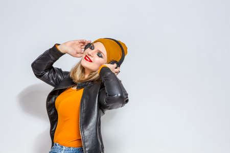 Portrait of Relaxing Caucasian Female Listening to Music Wearing Headphones. Posing in Leather...