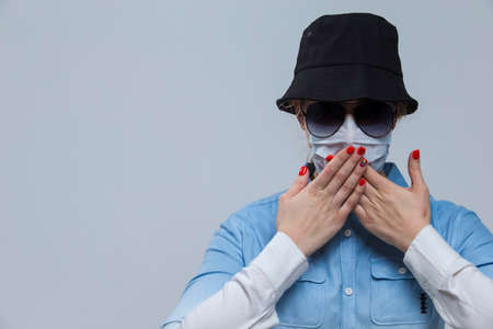 Virus Concepts. Ideas of Coronavirus of Depressed Caucasian Woman In Glasses And Black Hat Wearing Flu Virus Mask For Viral Prevention. Against Gray. Horizontal Imageの写真素材