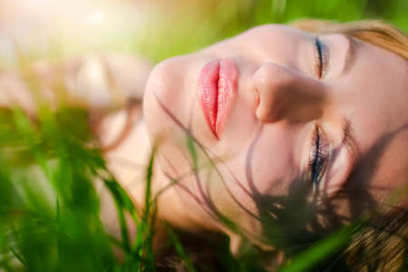 Closeup Portrait of Young Caucasian Blond Girl Resting on Green Meadow Outdoors.Horizontal Shot