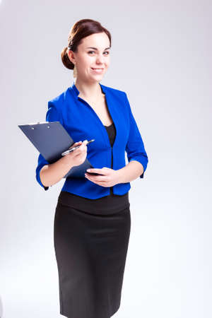 Smiling Happy Caucasian Entrepreneur in Blue Jacket Posing With Notepad and Pen In Studio. Against White. Vertical Compositionの写真素材