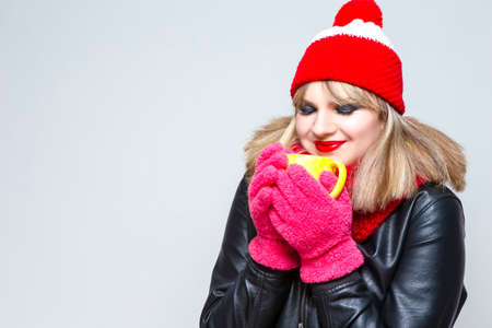 Winter Ideas. Natural Portrait of Relaxing Caucasian Blond Girl In Warm Hat and Scarf Against White With Teacup. Horizontal Shotの写真素材