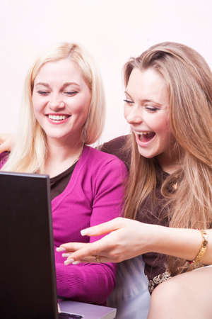 Youth Lifestyle Concepts. Two Happy Expressive Positive Caucaisan Girlfriends Having Fun. Working with Laptop Computer Indoors. Vertical image Orientationの写真素材