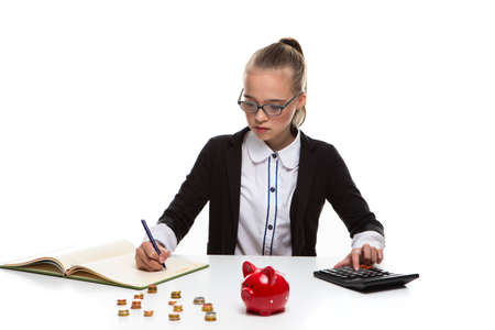 Money Saving Concepts. Teenager Blond Girl Posing With Coins and Moneybox. Calculating Income With Calculator For Savings.Horizontal Imageの写真素材