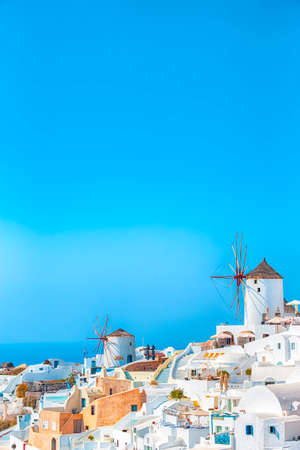Greek Traditional White Houses and Windmills of Oia or Ia at Santorini Island in Greece at Noon. Vertical Image Orientationの写真素材