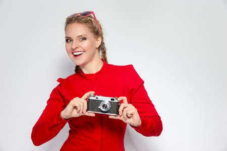Youth Ideas and Concepts. Cute and Positive Caucasian Blond Girl With Old School Film Camera in Red Dress with Sunglasses. Against White. Horizontal Shotの写真素材