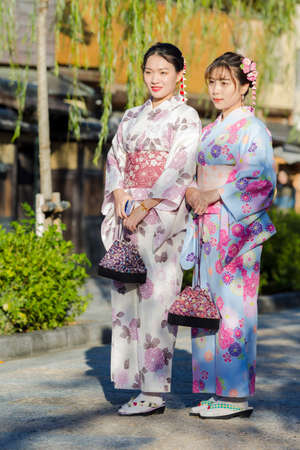 KYOTO, JAPAN - NOVEMBER, 8, 2019: Two Young Asian Girls Posing in Geisha Kimono in Traditional Japanese Environment in Kyoto, Japan.のeditorial素材