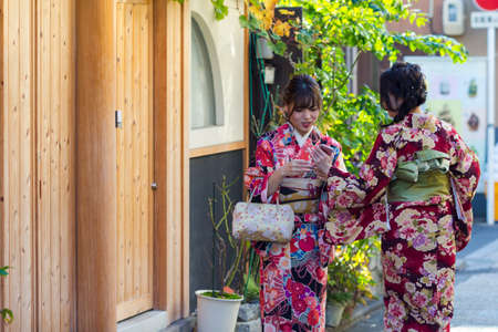 KYOTO, JAPAN - NOVEMBER, 8, 2019: Couple of  Young Japanese Girls Wearing Traditional Geisha's Kimono Taking Photos On Kyoto Street, Japan.のeditorial素材