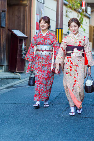 KYOTO, JAPAN - NOVEMBER, 8, 2019: Two Beautiful Japanese Geishas in Floral Silk Kimono in Traditional Environment in Kyoto, Japan.のeditorial素材