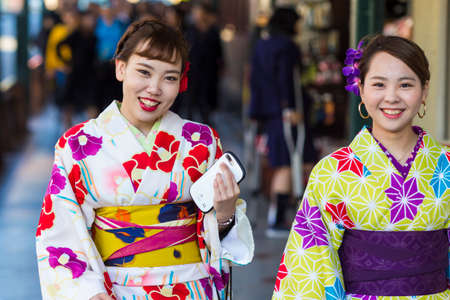 KYOTO, JAPAN - NOVEMBER, 8, 2019: Two Beautiful Japanese Geishas in Floral Silk Kimono in...