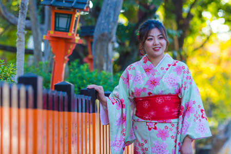 KYOTO, JAPAN - NOVEMBER, 8, 2019: Beautiful  Japanese Geisha Girl Posing in Floral Silk Kimono in Traditional Environment in Kyoto, Japan.のeditorial素材
