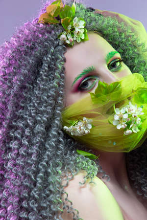 Virus Protection Ideas. Portrait of Positive Caucasian Girl With Frizzy Colorful Hair and Flowery Facial Protective Mask. Vertical Shotの写真素材