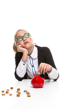 Children Frugal Concepts. Portrait of Thoughtful Dreaming Teenage Girl Wearing Glasses. Posing With Coins and Moneybox and Coins.Vertical Imageの写真素材
