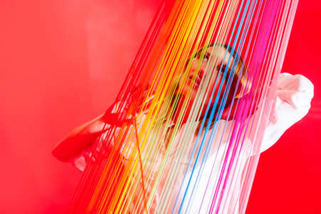 Portrait of Dreaming Tranquil Female Woman Posing Behind Colorful Thread Stripes.Horizontal Image Compositionの写真素材