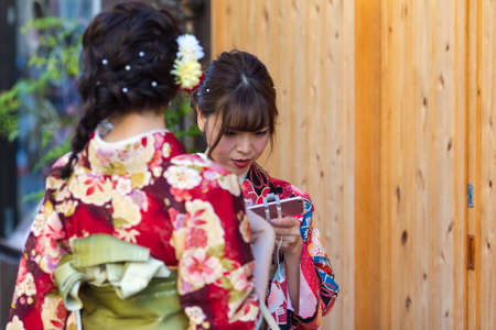 KYOTO, JAPAN - NOVEMBER, 8, 2019: Couple of  Young Japanese Girls Wearing Traditional Geisha's Kimono Taking Photos On Kyoto Street, Japan.のeditorial素材