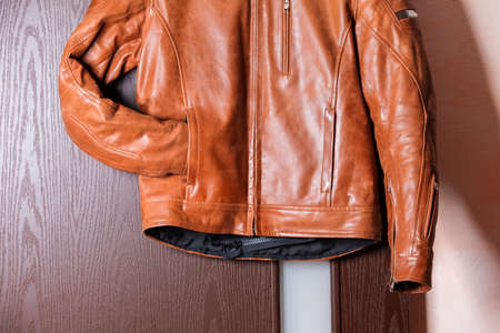 Closeup of Tanned Leather Stylish Motorcyclist Jacket Hinged Over Sliding Door Holder. Horizontal Compositionの写真素材