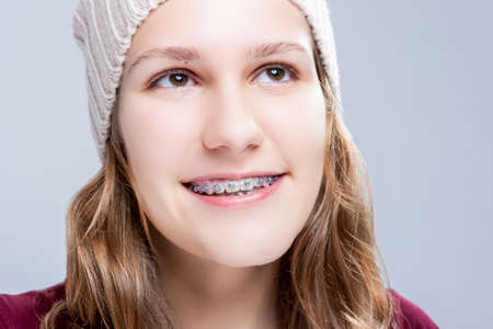 Teenage Ideas. Happy Laughing Caucasian Teenager Girl Wearing Teeth Brackets. Posing Against Gray....