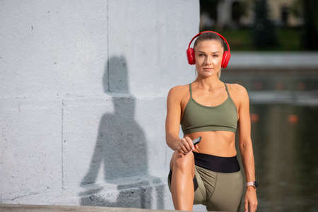 Professional Caucasian Female Athlet In Running Outfit During Her Stretching Exercises Outdoor....