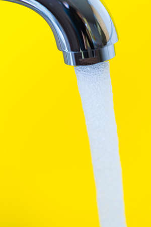 Macro Shoot of New Silver Water Tap Against Yellow Background.Vertical image
