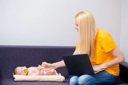 Portrait of Young Caucasian Mother WIth Baby Boy Remote Working Using Laptop. Horizontal Image