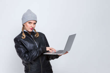 Portrait of Caucasian Blond Girl in Warm Hat and Leather Jacket With Laptop. Horizontal Imageの写真素材