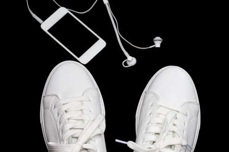 Sport Concepts. Pair of New White Sneakers Together with Music Player and Headphones On Black. Horizontal Orientationの写真素材