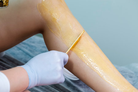 Body care and Spa Concepts. Close-up of Beautician Preparing for Wax Depilation of Woman Legs By Applying Liquid Wax With Spatula on Female Legs in Beauty Salon.Hの写真素材