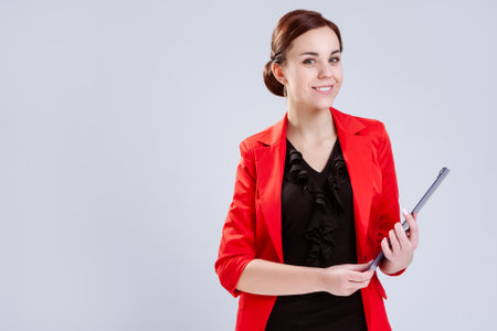 Portrait of Smiling Caucasian Entrepreneur in Red Jacket Posing With Notepad In Studio. Against White. Vertical Compositionの写真素材