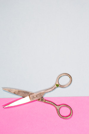 Pair of Old Used Metal Rusty Scissors Placed Over Pink And Blue Paper Background. Vertical image