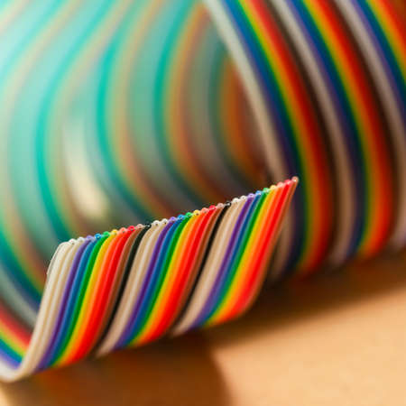 Roll of Colorful Twisted Connecting Wire Strip on Flat Surface with Added Light Flares. Square image...