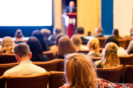 Lecturer In Front of the White Screen on Stage for the Group of Business People at a  Conference. Horizontal Imageの写真素材