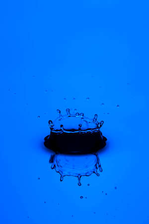 Closeup Macro Image of Abstract Blue Water Splash With Multiple Droplets Falling on Water Surface. Vertical Shotの写真素材