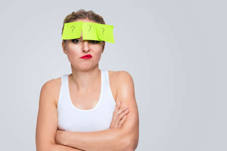 Caucasian Female in White Bra With Yellow Sticky Note on Her Forehead. Against White Background....