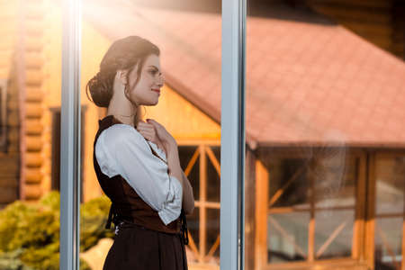 Portrait of Young Caucasian Woman in Old Medieval Dress Praying in Front of Large Glass Window. Horizontal Compositionの写真素材