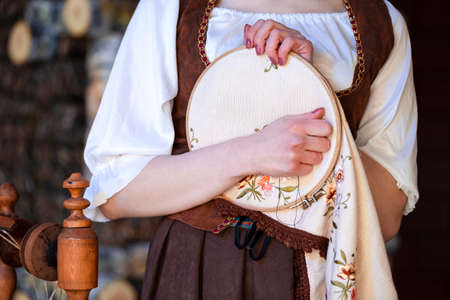Young Caucasian Brunette Woman Posing With Fancywork Hoop in Retro Dress In Rural Environment. Horizontal image Compositionの写真素材
