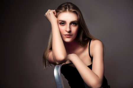 Natural Sensual Portrait of Charming Caucasian Blond Girl With Long Beautiful Hair Posing in Studio Against Dark Background. Horizontal Imageの写真素材