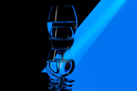Glassware Concepts. Three Different in Height Glass Cups Placed in One Line Against Black And Blue Background. Horizontal Compositionの写真素材