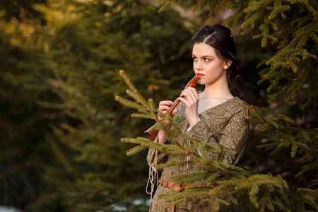 Portrait of Charming Caucasian Brunette Female in Old Medieval Green Dress With Flute Against...