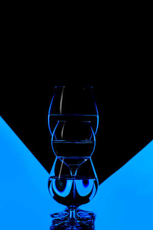 Three Different Glass Cups Placed in One Line Against Black And Blue Background. Vertical Compositionの写真素材
