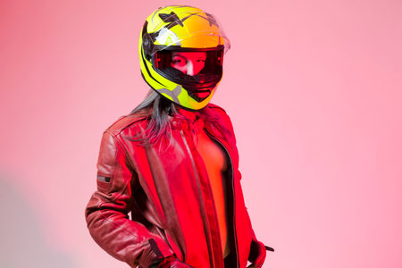 Sexy Caucasian Female Motorcyclist Posing In Leather Protective Jacket And Helmet Over Pink...